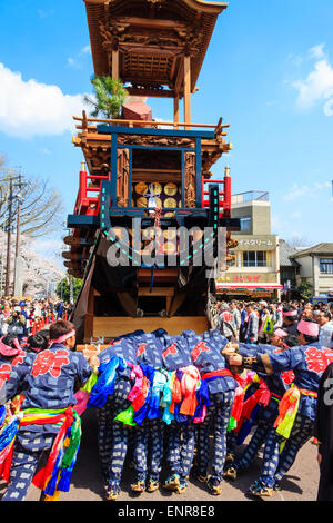 Équipe d'hommes luttant pour pousser un dashi massif, yama, float en bois, entouré de foules de touristes regardant au festival de printemps Inuyama Banque D'Images