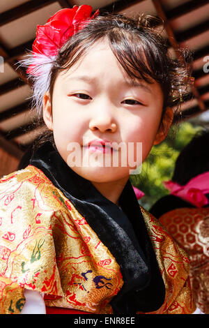 Enfant japonais, fille, 7-8 ans, habillé en costume traditionnel, et assis dans un char de yama à un festival, tourné pour regarder le spectateur. Sourire. Banque D'Images