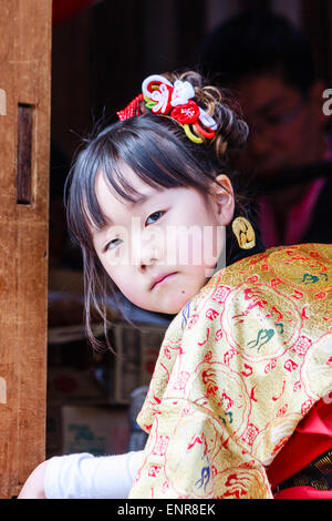 Enfant japonais, fille, 7-8 ans, habillé en costume traditionnel, kimono, et assis dans un char de yama à un festival, tourné à regarder le spectateur. Banque D'Images