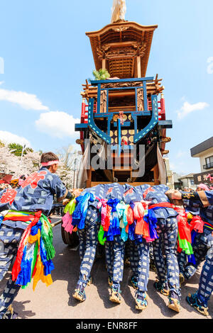 Équipe d'hommes luttant pour pousser un dashi massif, yama, float en bois, entouré de foules de touristes regardant au festival de printemps Inuyama Banque D'Images