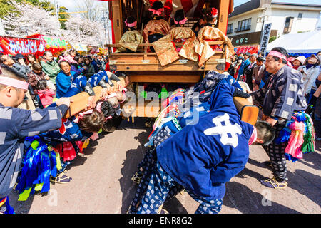 Équipe d'hommes luttant pour pousser un dashi massif, yama, float en bois, entouré de foules de touristes regardant au festival de printemps Inuyama Banque D'Images