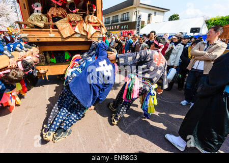 Équipe d'hommes luttant pour pousser un dashi massif, yama, float en bois, entouré de foules de touristes regardant au festival de printemps Inuyama Banque D'Images