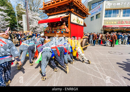 Équipe d'hommes luttant pour pousser un dashi massif, yama, float en bois, entouré de foules de touristes regardant au festival de printemps Inuyama Banque D'Images