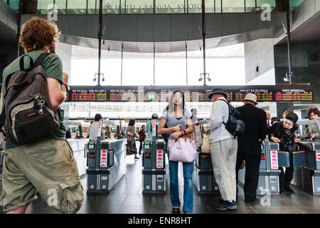 Les personnes qui traversent les barrières automatiques de billets avec affichage numérique de la plate-forme et des informations sur les trains à la gare de Kyoto pendant la journée. Banque D'Images