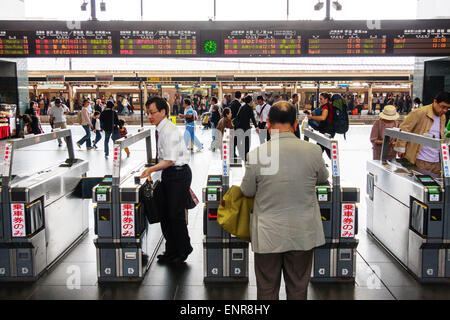 Les personnes qui traversent les barrières automatiques de billets avec affichage numérique de la plate-forme et des informations sur les trains à la gare de Kyoto pendant la journée. Banque D'Images