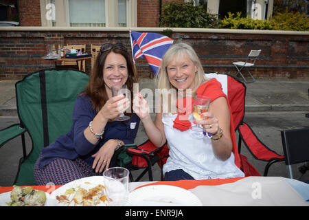 La victoire en Europe le 70 e anniversaire du Parti de la rue. Agitant un drapeau de Jack d'Union et profitant d'un verre de vin, deux femmes adultes résidant dans une communauté à Southsea, Hampshire, Angleterre, profitez d'une fête de rue pour célébrer le 70ème anniversaire de VE Day. Banque D'Images