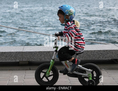 Un jeune garçon en train de rouler à vélo sur la promenade à Harbourfront à Toronto. Banque D'Images