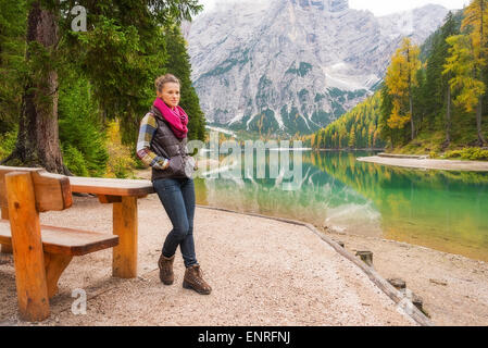 Une femme brune portant des randonneurs de l'équipement de plein air se tient en appui sur une table de pique-nique en bois le long du bord du lac Bries. L'eau Banque D'Images