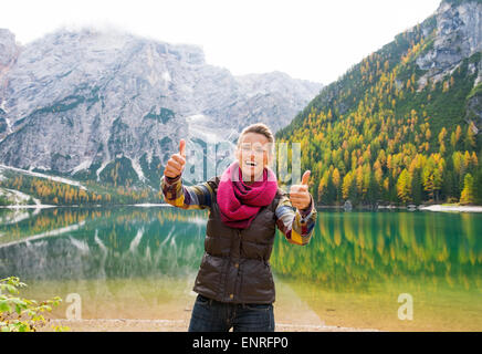 Un sourire et rire brunette holding deux pouces vers le haut dans l'approbation tout en se tenant sur les rives du lac Bries. Dans l'arrière-plan, Banque D'Images