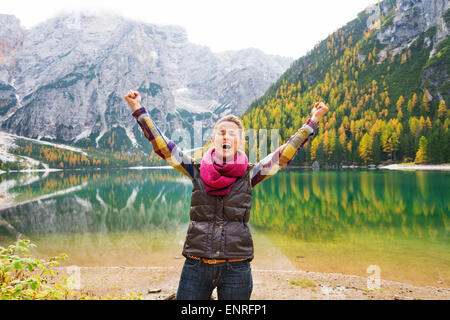 Un heureux, smiling woman hiker cheers de joie sur les rives du lac Bries. Dans l'arrière-plan, l'eau reflète encore l'automne co Banque D'Images