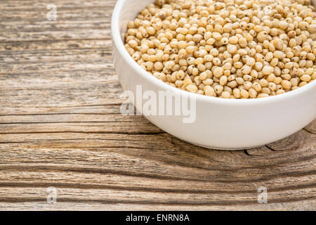 Sans gluten, grain du sorgho blanc dans un petit bol en céramique en bois veiné contre Banque D'Images