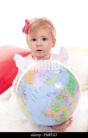 Cute blonde baby girl holding globe et assis sur blanket Banque D'Images