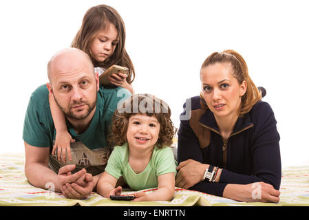 Joyeuse famille avec deux enfants portant sur blanket against white background Banque D'Images