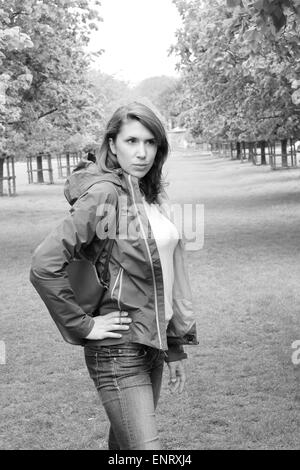 Jeune femme portant un manteau en champ bordé d'arbres Banque D'Images