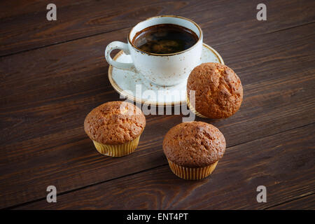 Tasse de café blanc et trois petits gâteaux sur fond en bois foncé Banque D'Images