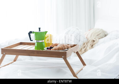 Plateau de bois de petit-déjeuner avec café et croissant sur le lit Banque D'Images