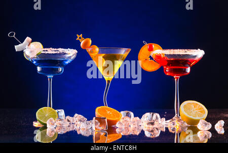 Martini de boissons servis sur une table en verre avec différentes couleurs de fond sombre Banque D'Images