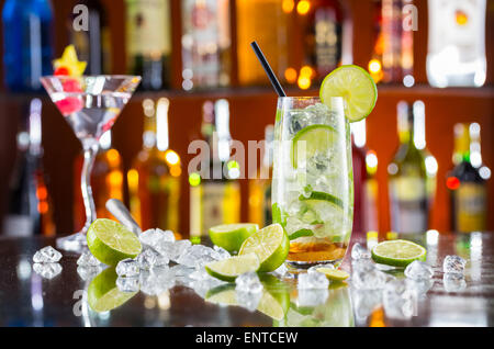 Mojito cocktail verre sur comptoir bar avec des bouteilles sur fond flou Banque D'Images