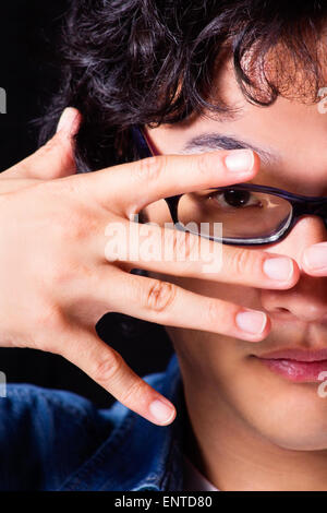 Asian young man looking through mains porter des lunettes Banque D'Images