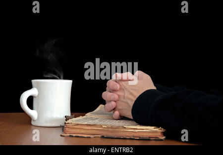 Woman's hands repliées dans la prière sur un porté la Sainte Bible avec tasse à café blanc. Banque D'Images