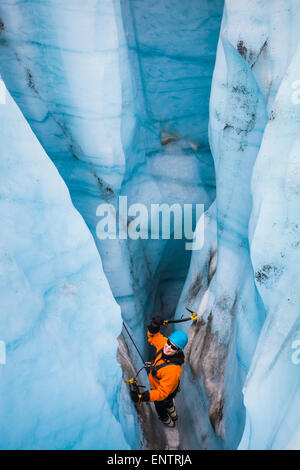 Un grimpeur sur glace balançoires sa glace outils dans un moulin sur le glacier en racine Wrangell-St. Elias National Park, Alaska. Banque D'Images