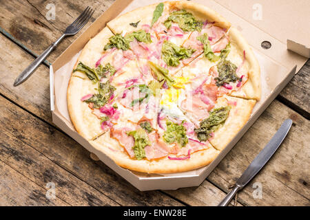 Menu Pizza recette et arrière-plan. Gourmet Pizza dans une boîte avec l'argenterie sur la table en bois. Banque D'Images