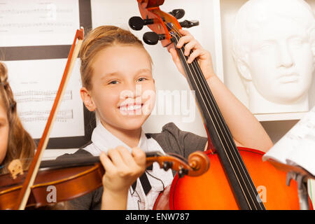 Smiling girl détient violoncelle avec d'autres ami près de Banque D'Images