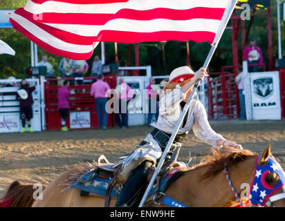 Une cowgirl porte le drapeau américain à la cérémonie d'ouverture à l'Cornyval PRCA Rodeo Texas Helotes près de San Antonio Banque D'Images