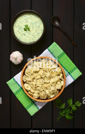 Tortellini cuites farcies de fromage dans un bol en bois avec une sauce à la crème de persil Banque D'Images