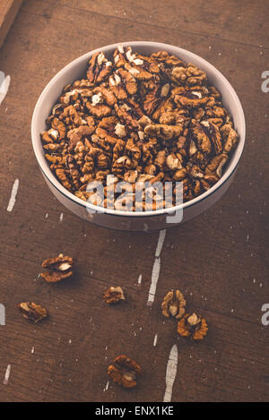 Les cerneaux de noix décortiquées dans un bol en céramique sur la planche en bois rustique marron Background Banque D'Images