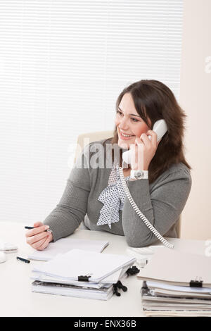Smiling young business woman on phone at office Banque D'Images