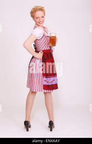 Jeune femme dans la dirndl avec full beer mug regarde au-dessus de l'épaule Banque D'Images