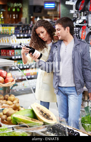 L'heureux couple choisit une bouteille de vin dans la boutique Banque D'Images