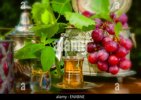 Thé à la menthe et les raisins rouges sur le tableau d'Arabie dans le jardin Banque D'Images