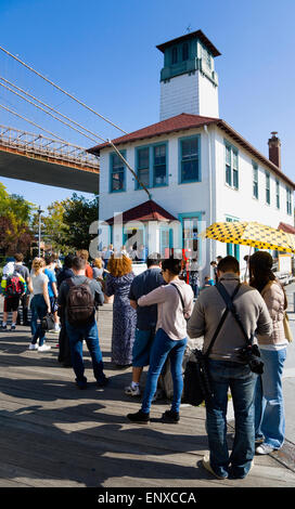 USA, New York State, New York, NYC, Brooklyn Bridge Park, file d'attente de clients à la Brooklyn Ice Cream Factory dans un vieux hangar à bateaux sur le Fulton Ferry Pier sous le pont suspendu. Banque D'Images