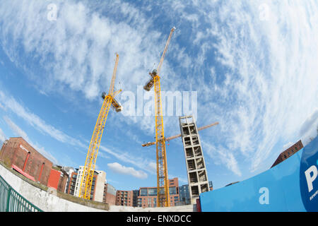 Grues à tour jaune contre un ciel bleu avec nuages fragmentés en formation Banque D'Images