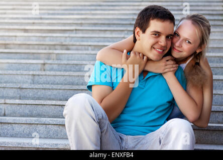 Jeune couple d'amoureux assis sur des escaliers et embrasser Banque D'Images