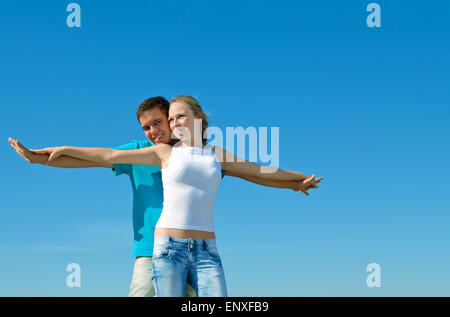Belle jeune couple contre le ciel bleu Banque D'Images