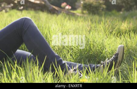 Jambes allongé dans l'herbe dans un parc Banque D'Images