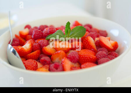 Bol de fraises, framboises et crème avec cuillère en argent Banque D'Images
