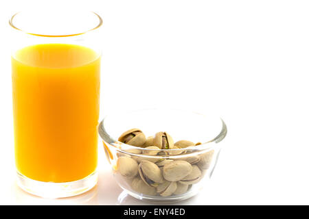 Les pistaches dans une plaque de verre et verre de jus d'orange isolated on white Banque D'Images