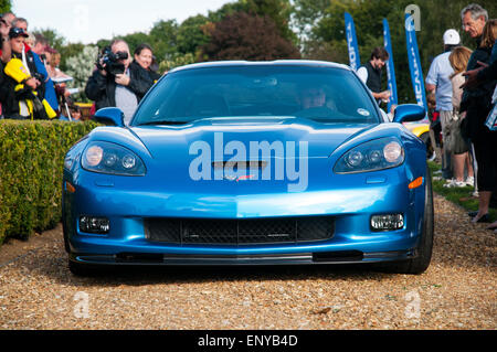 Vue avant d'un modèle bleu, Fin-voiture de sport Corvette américaine sur une route de gravier avec un chauffeur, et plusieurs aux curieux à proximité. Banque D'Images