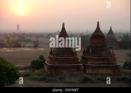 Les silhouettes sombres des temples contre le ciel rougeoyant jaune au lever de Bagan Myanmar Banque D'Images