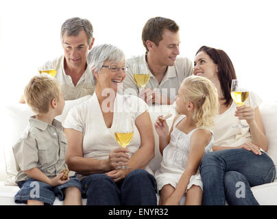 Famille dans le salon boire du vin et manger des biscuits Banque D'Images