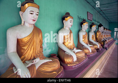 Longue rangée de Bouddhas en pierre peint contre un mur du temple vert dans l'ancienne capitale du Myanmar Sagaing Banque D'Images