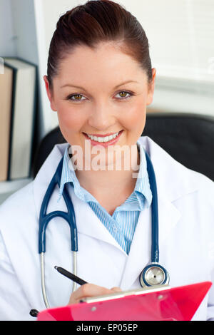 Confident female doctor smiling at the camera tenant un presse-papiers Banque D'Images