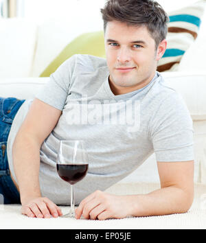 Beau jeune homme avec verre gisant sur le sol Banque D'Images