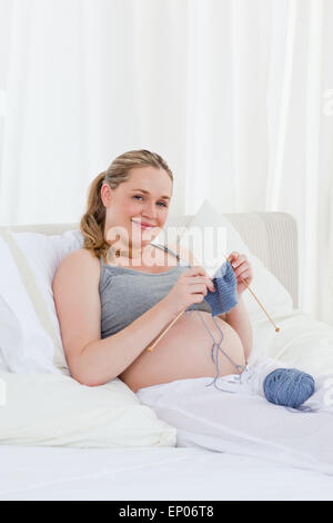 Adorable femme enceinte sur son lit de tricot Banque D'Images