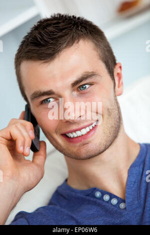 Beau jeune homme parlant au téléphone dans la salle de séjour Banque D'Images