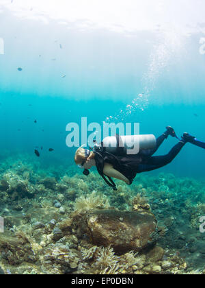 Plongeur femelle planant au-dessus d'une barrière de corail à Tulamben, Bali Indonésie Banque D'Images